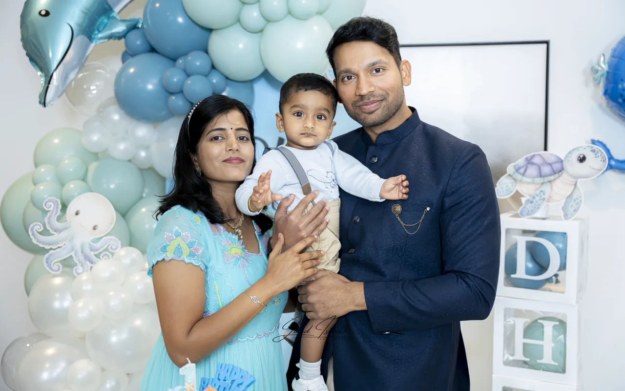A family of three in front of a balloon arch
